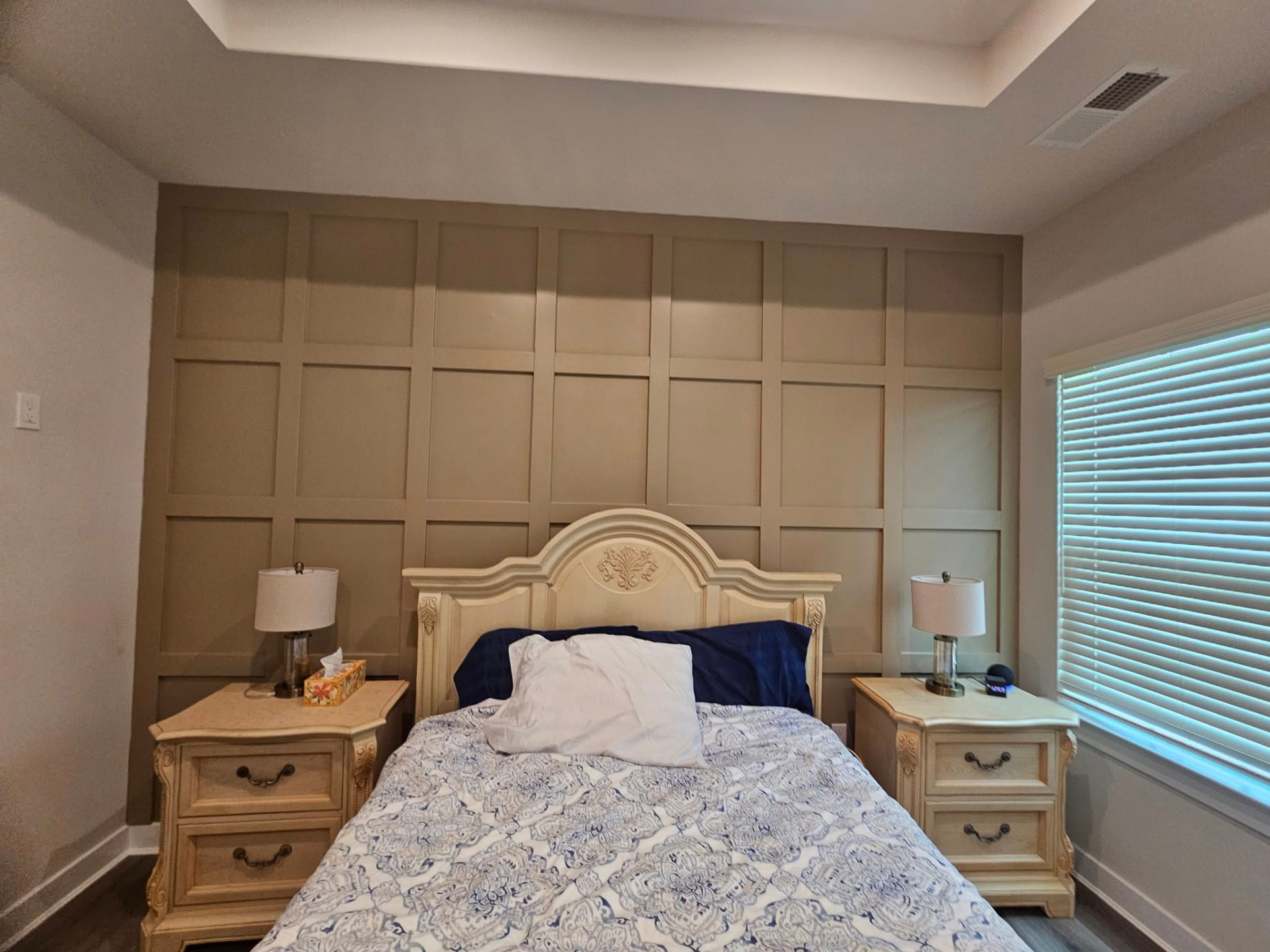 Finished floor-to-ceiling board and batten grid wall painted warm greige behind a bed