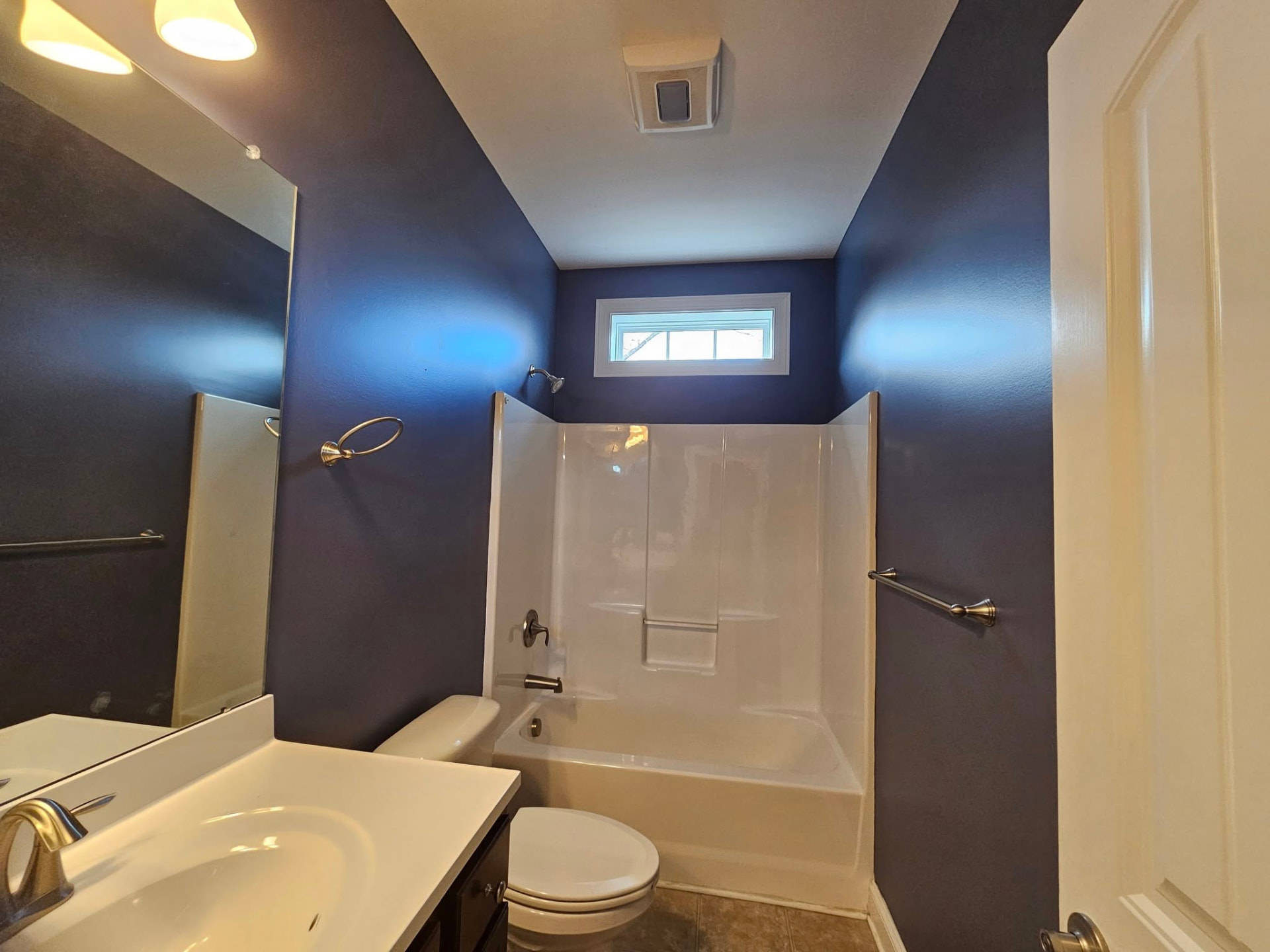 Same bathroom painted deep navy with a bright white ceiling and trim