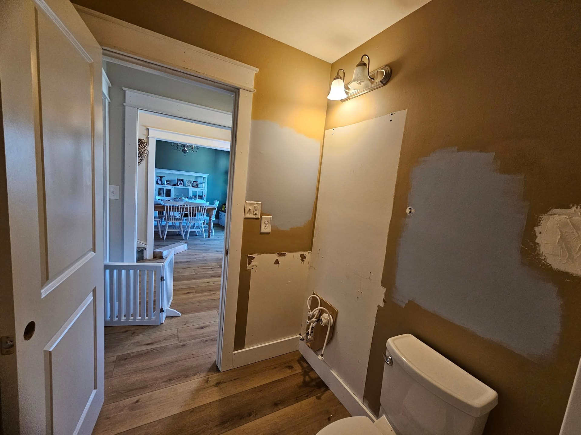 Bathroom mid-project with tan walls, primer patches, and exposed drywall repairs