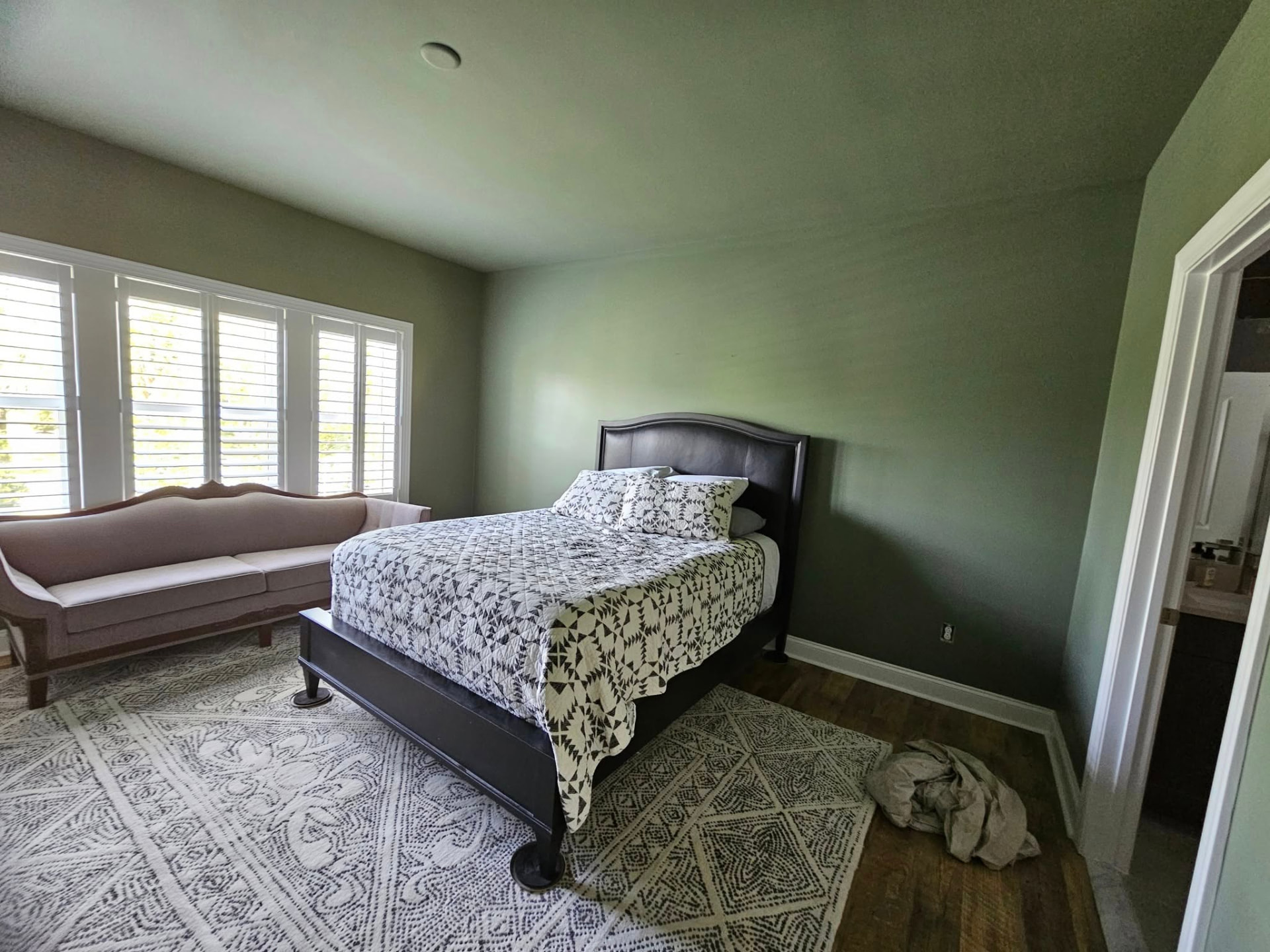 Bedroom finished in a soft sage green on walls and ceiling with white trim and plantation shutters
