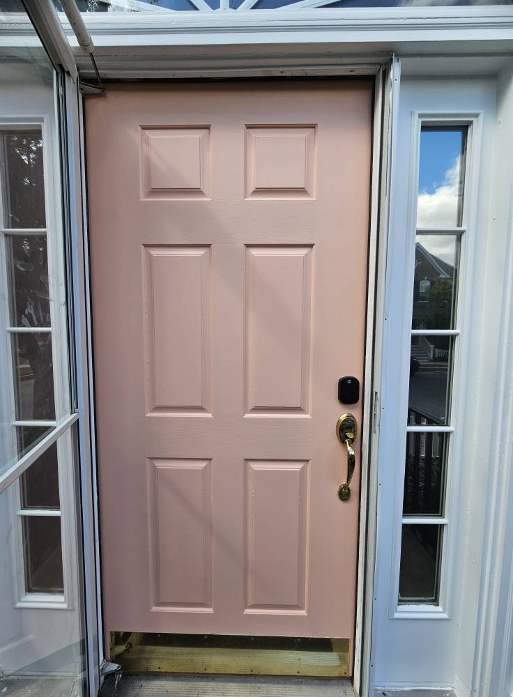Same front door repainted a soft blush pink against white trim and brass hardware