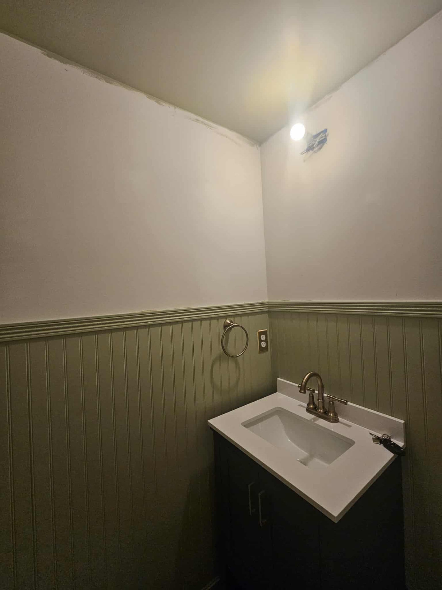 Powder room with plain white walls above sage beadboard wainscot before wallpapering