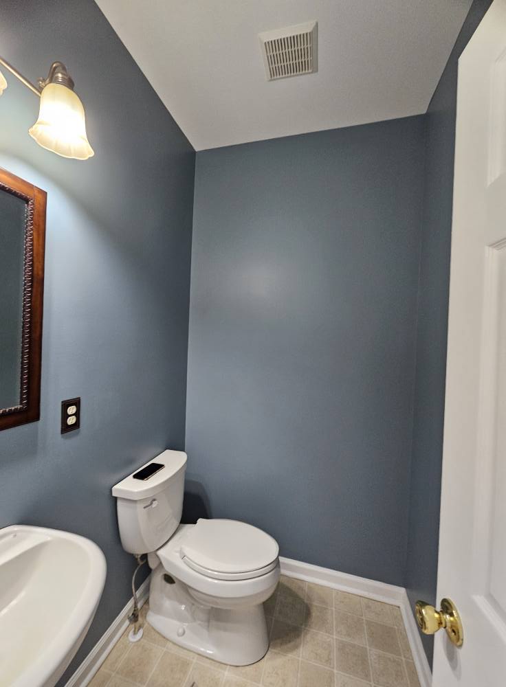Powder room painted a soft blue-grey with white trim and a white ceiling
