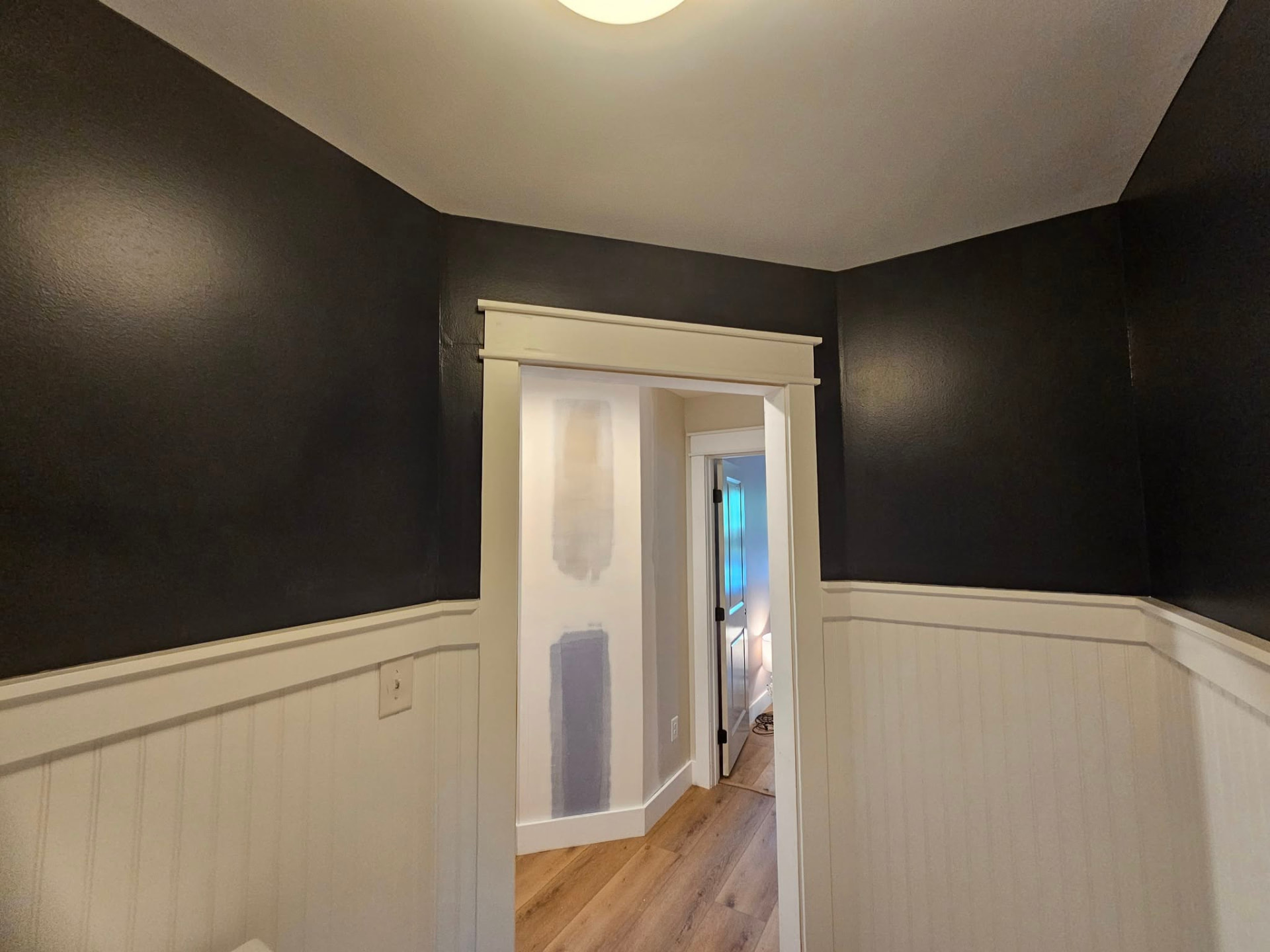Laundry room with near-black upper walls above cream beadboard wainscot and craftsman door casing