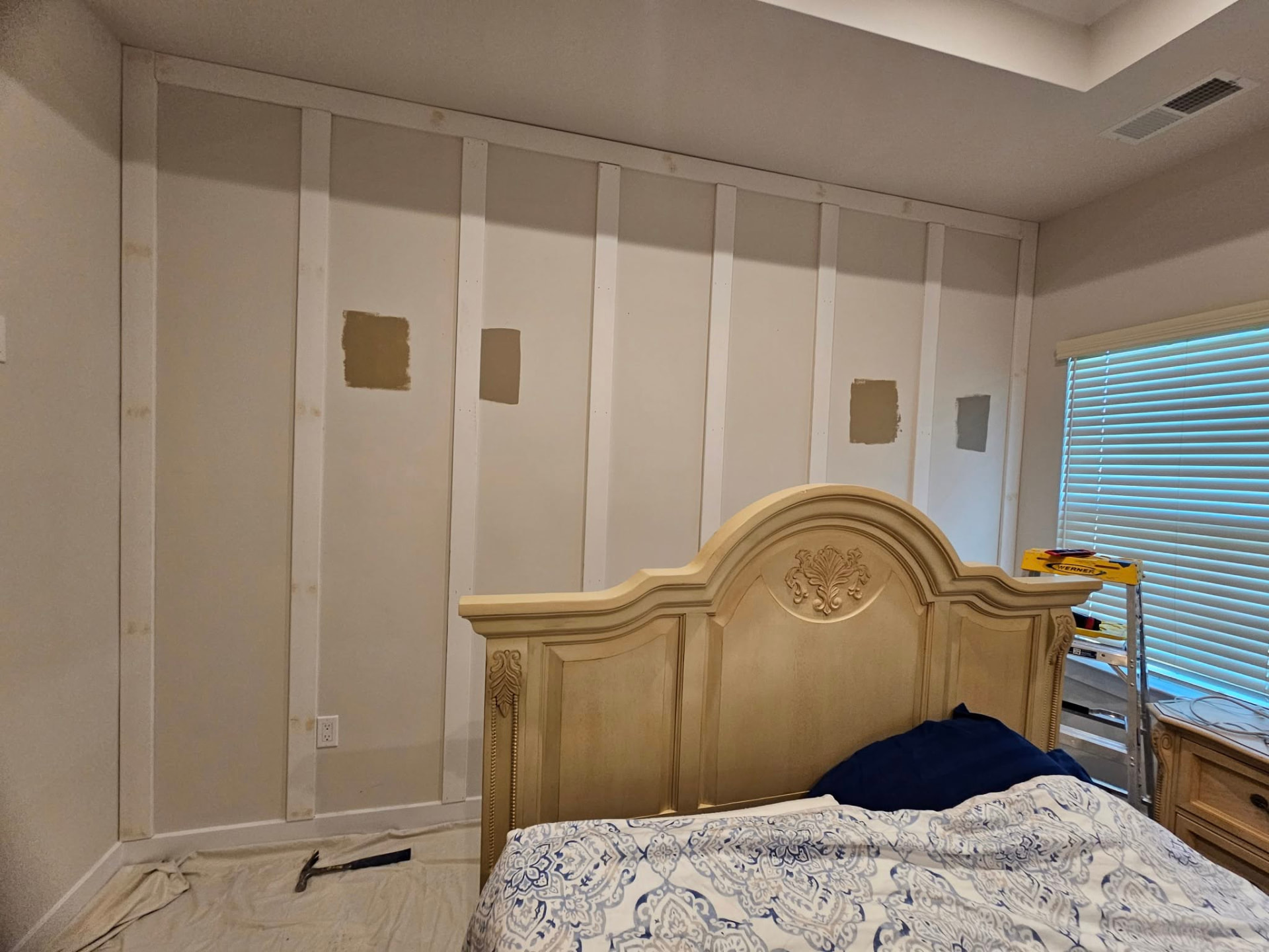 Bedroom wall with raw board and batten trim installed and unpainted color samples