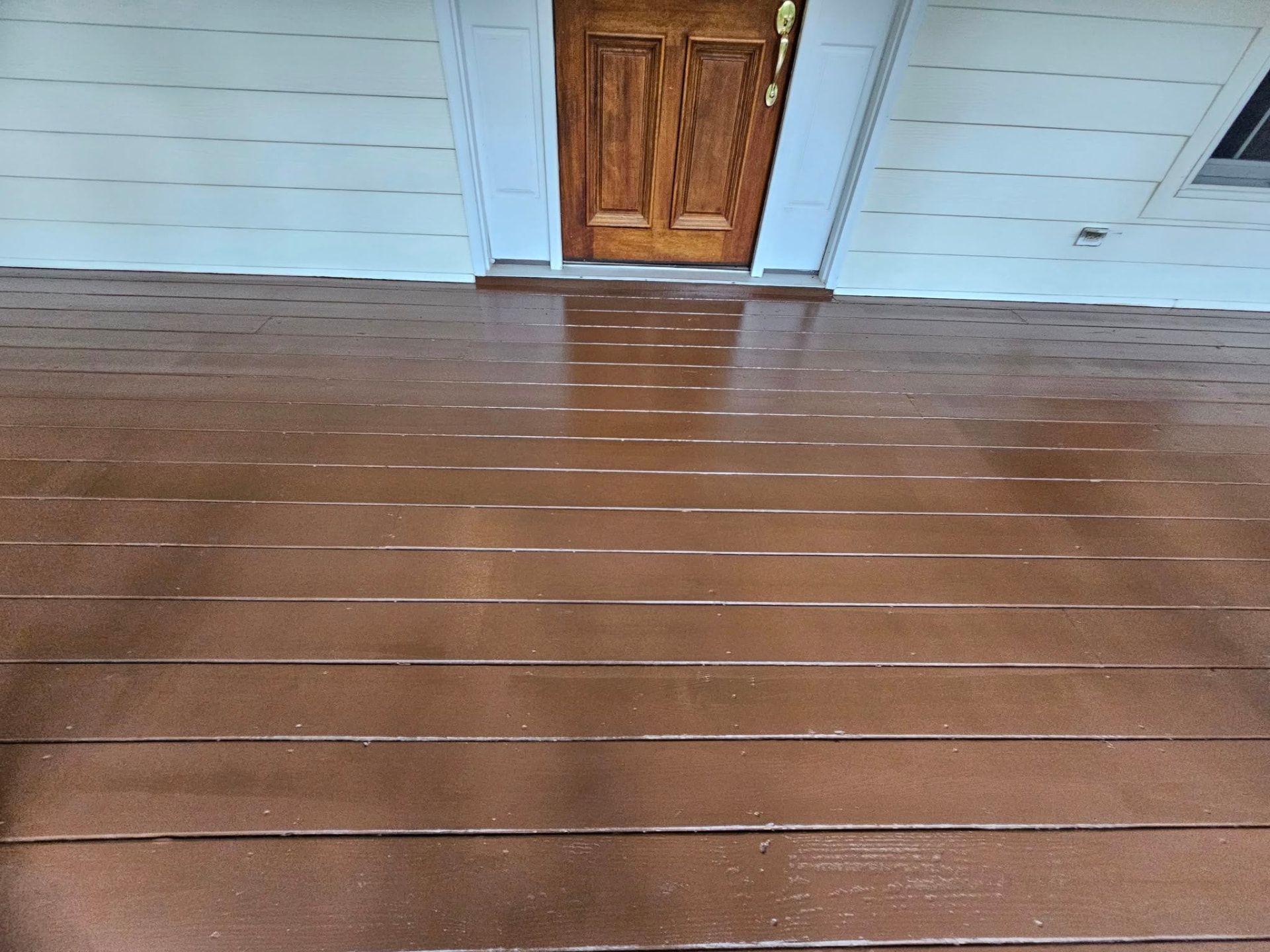 Close-up of freshly stained porch boards with an even finish running to the front door