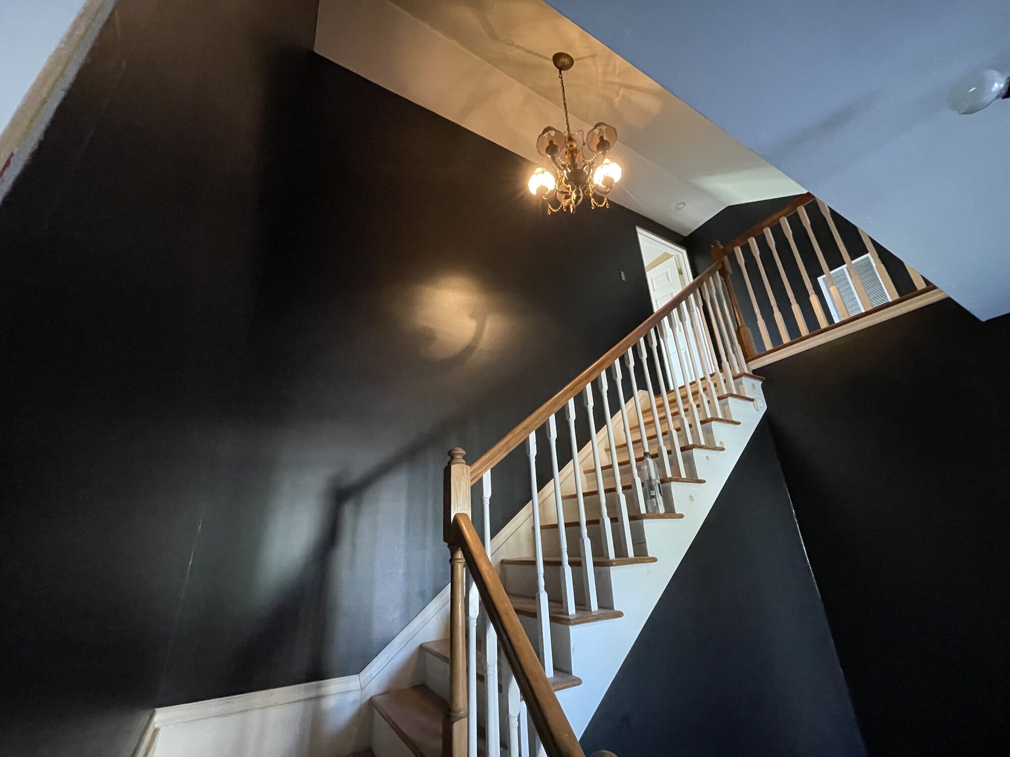 Two-story stairwell painted charcoal with white risers and an oak handrail