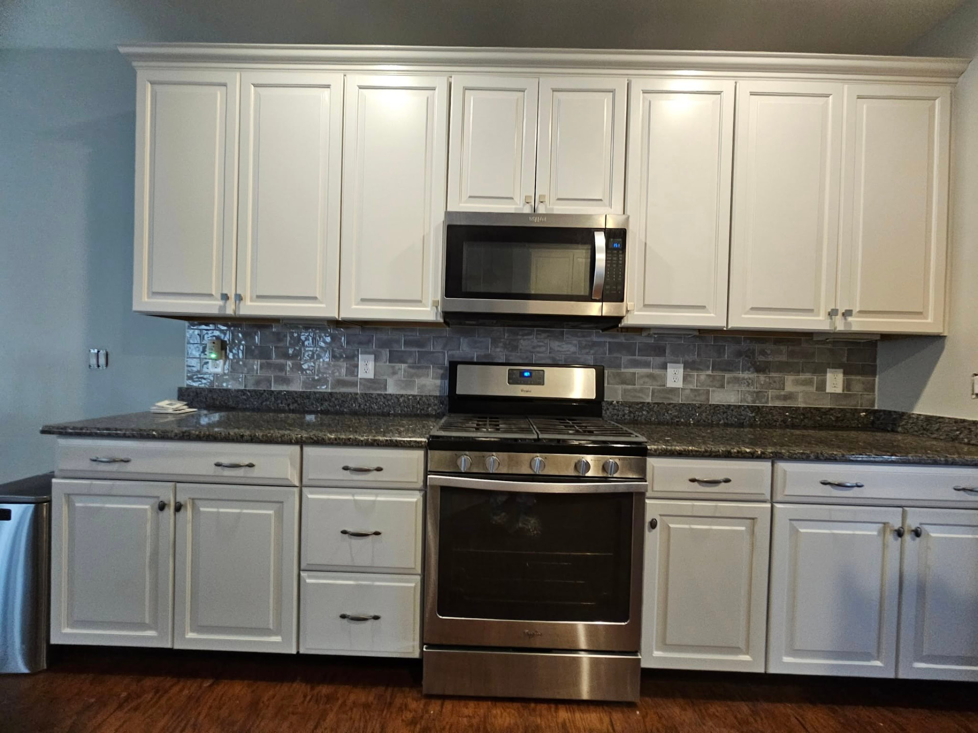Same kitchen with cabinets refinished in warm white, brightening the whole room