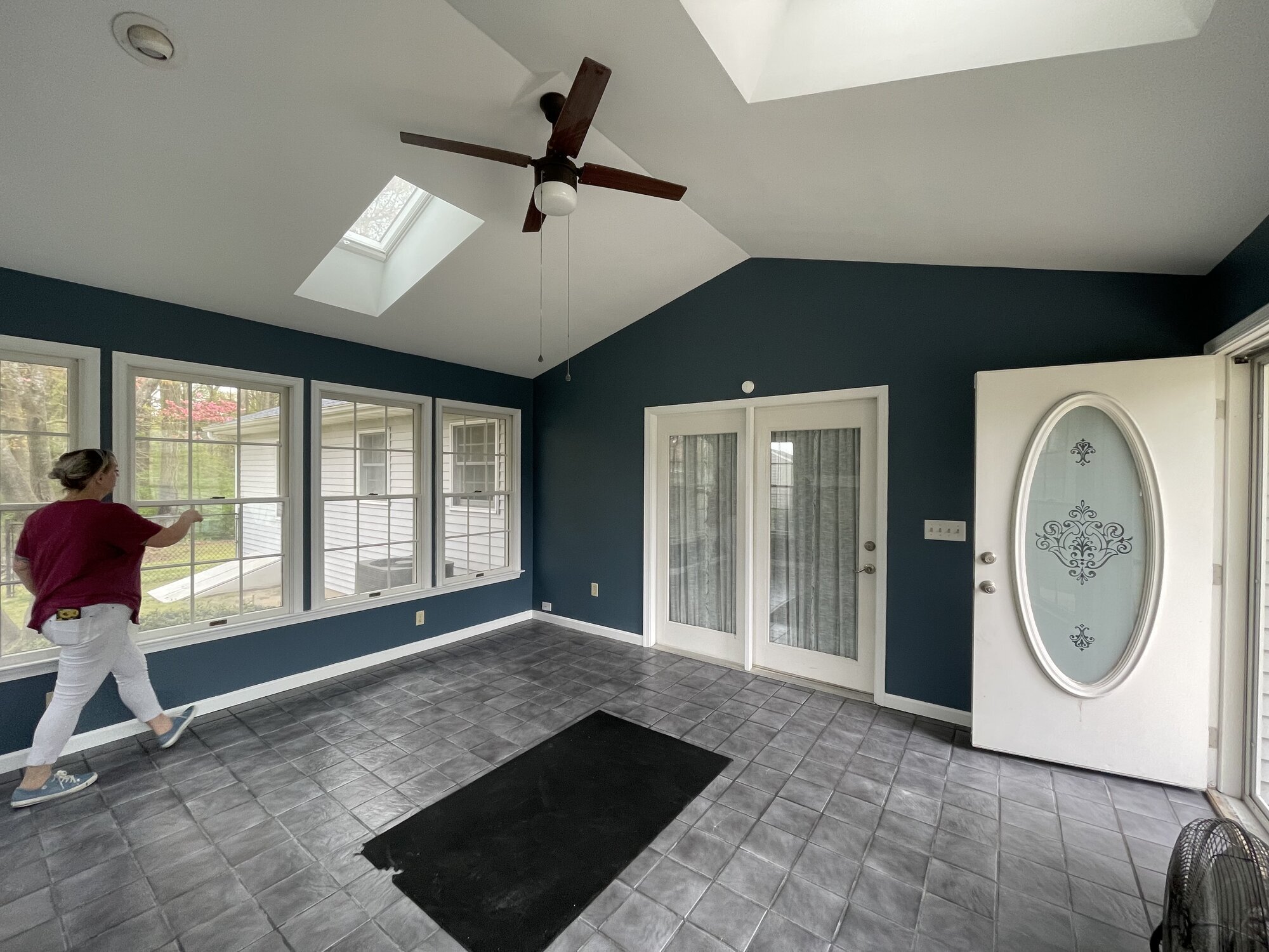 Sunroom mid-project with deep blue walls, skylights, and freshly cut-in white window trim