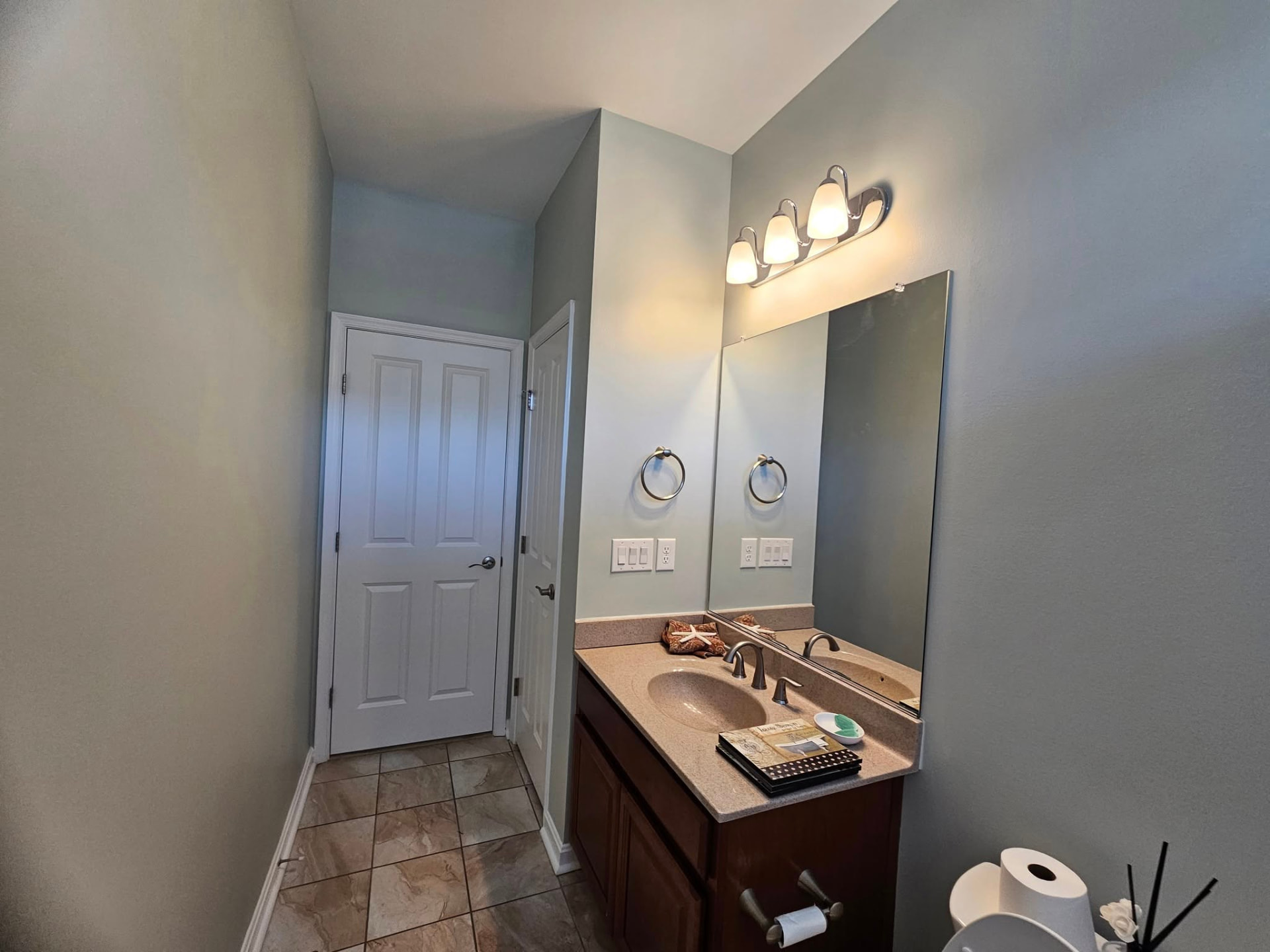 Same hall bathroom repainted a soft coastal grey-green with crisp white trim
