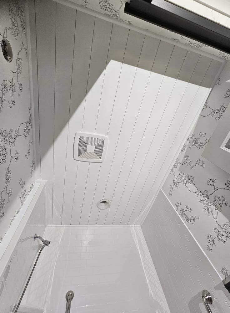 Bathroom shower area with a white painted shiplap ceiling and floral line-drawing wallpaper