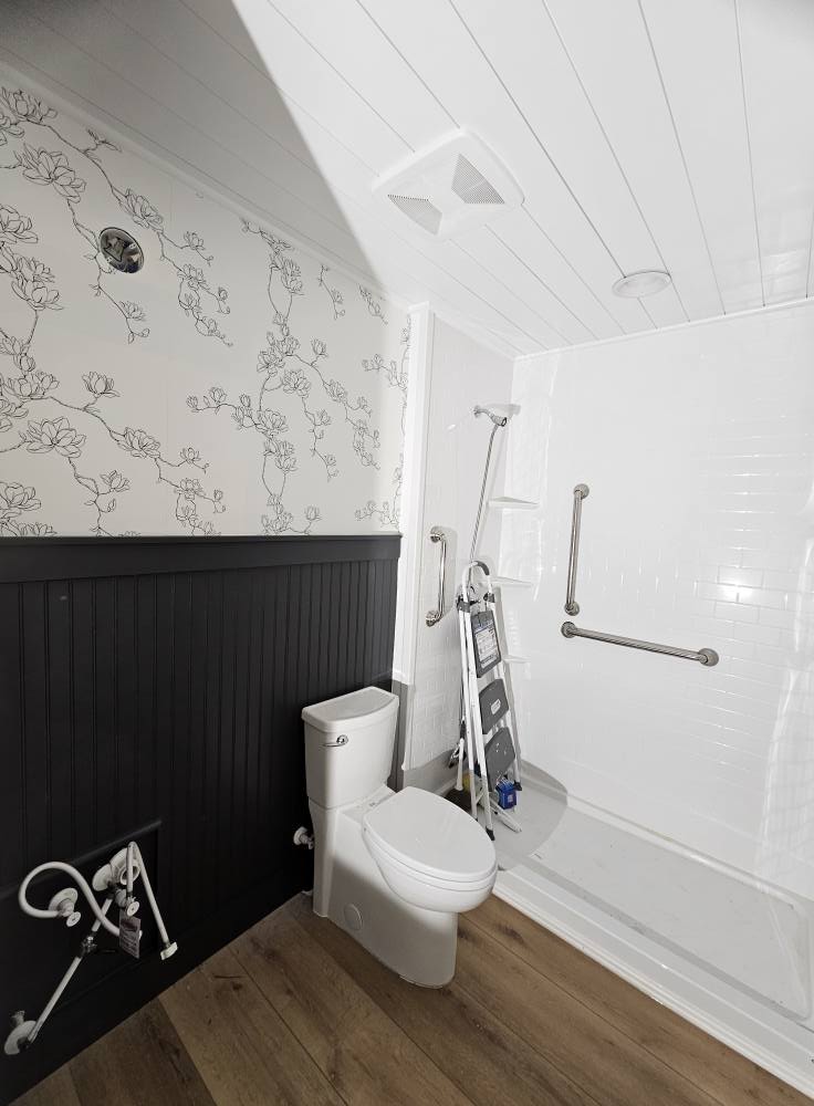 Finished guest bathroom with magnolia wallpaper, charcoal beadboard wainscot, and a white shiplap ceiling