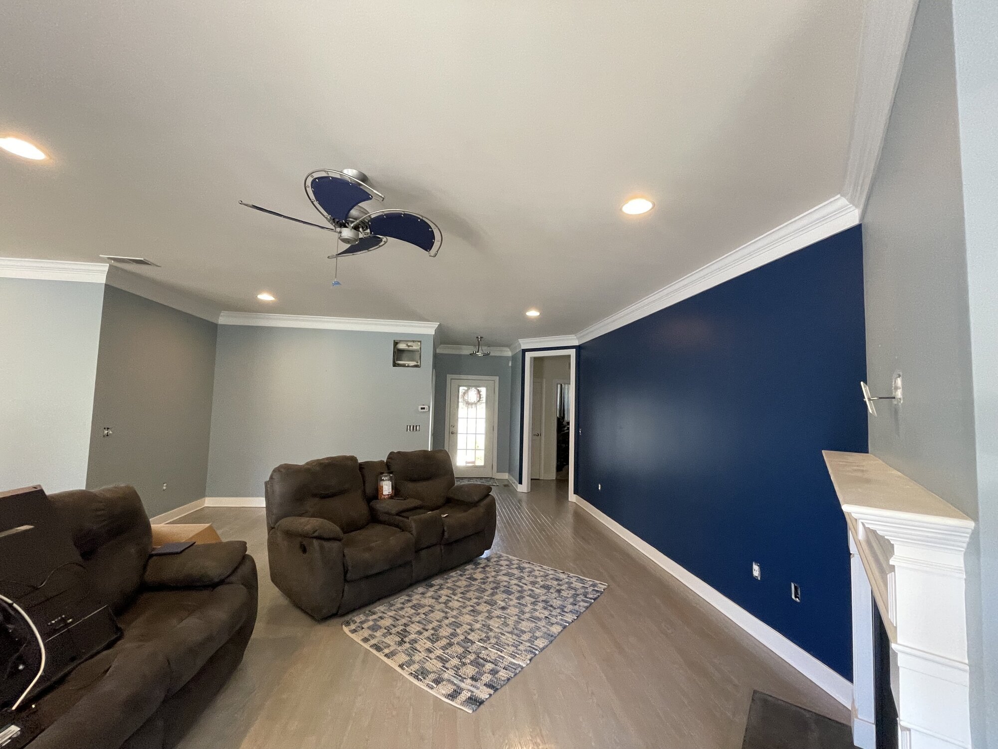 Living room with a full navy accent wall beside soft blue-grey walls and white crown moulding