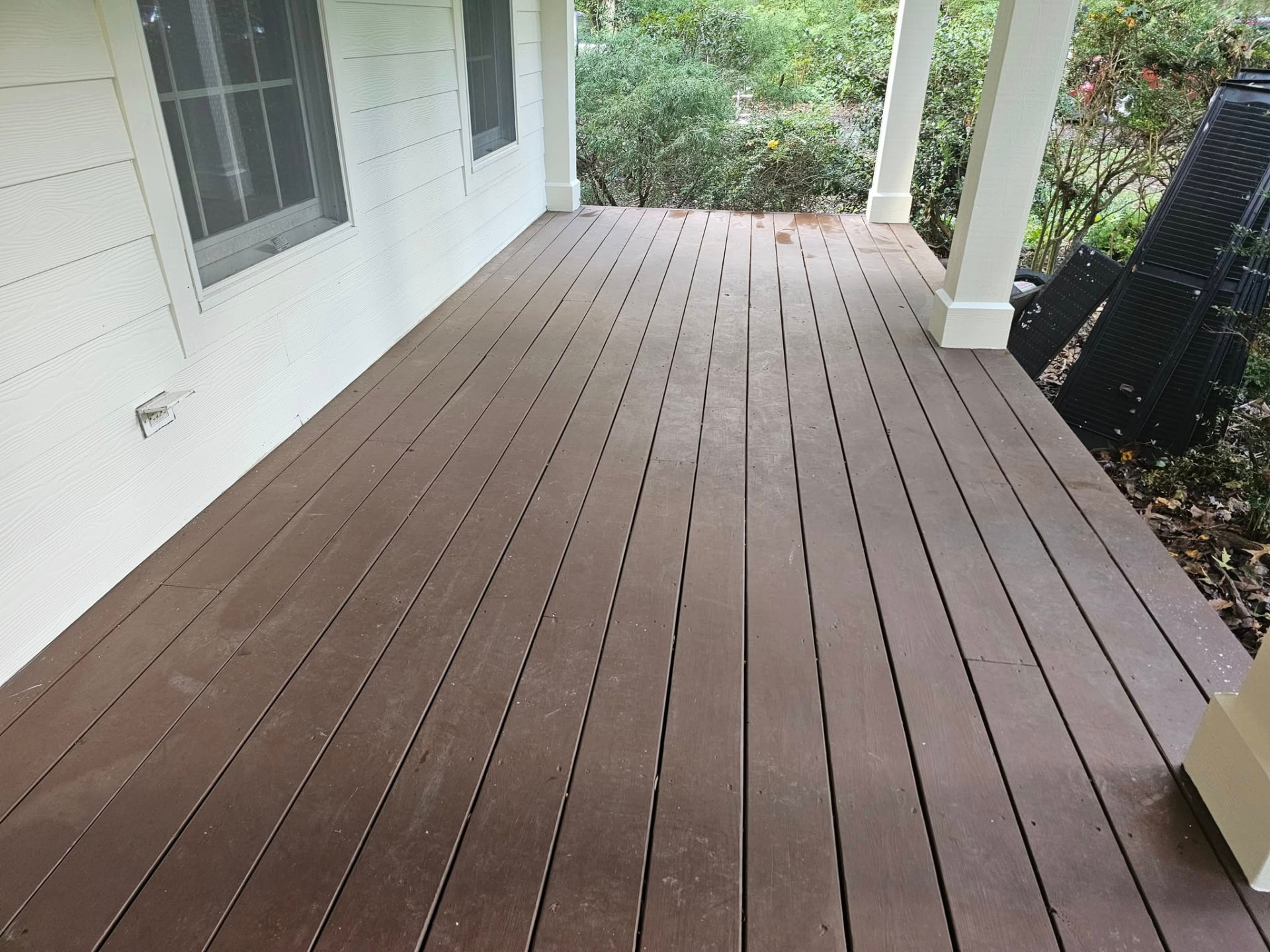 Covered porch with faded, worn brown deck boards before restaining