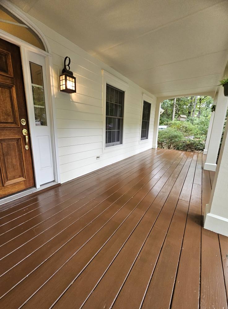 Same covered porch with freshly stained warm brown boards against white siding