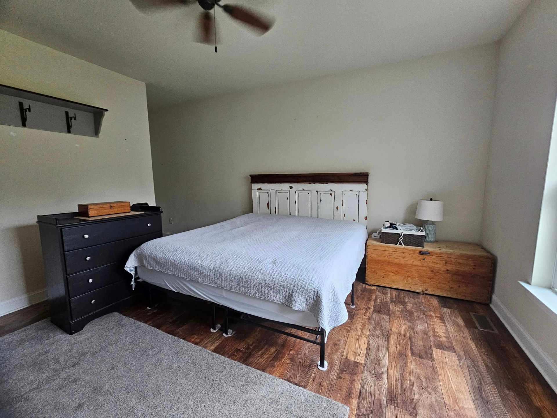 Bedroom with flat beige walls and dark wood floors before repainting