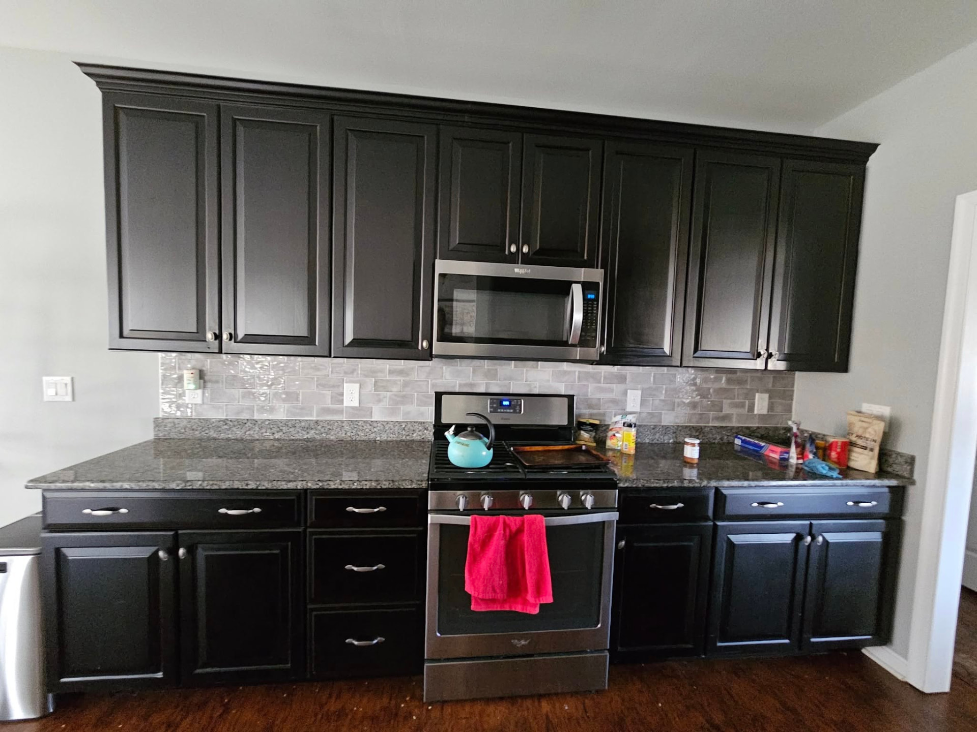 Kitchen with dark espresso cabinets and a grey tile backsplash before refinishing