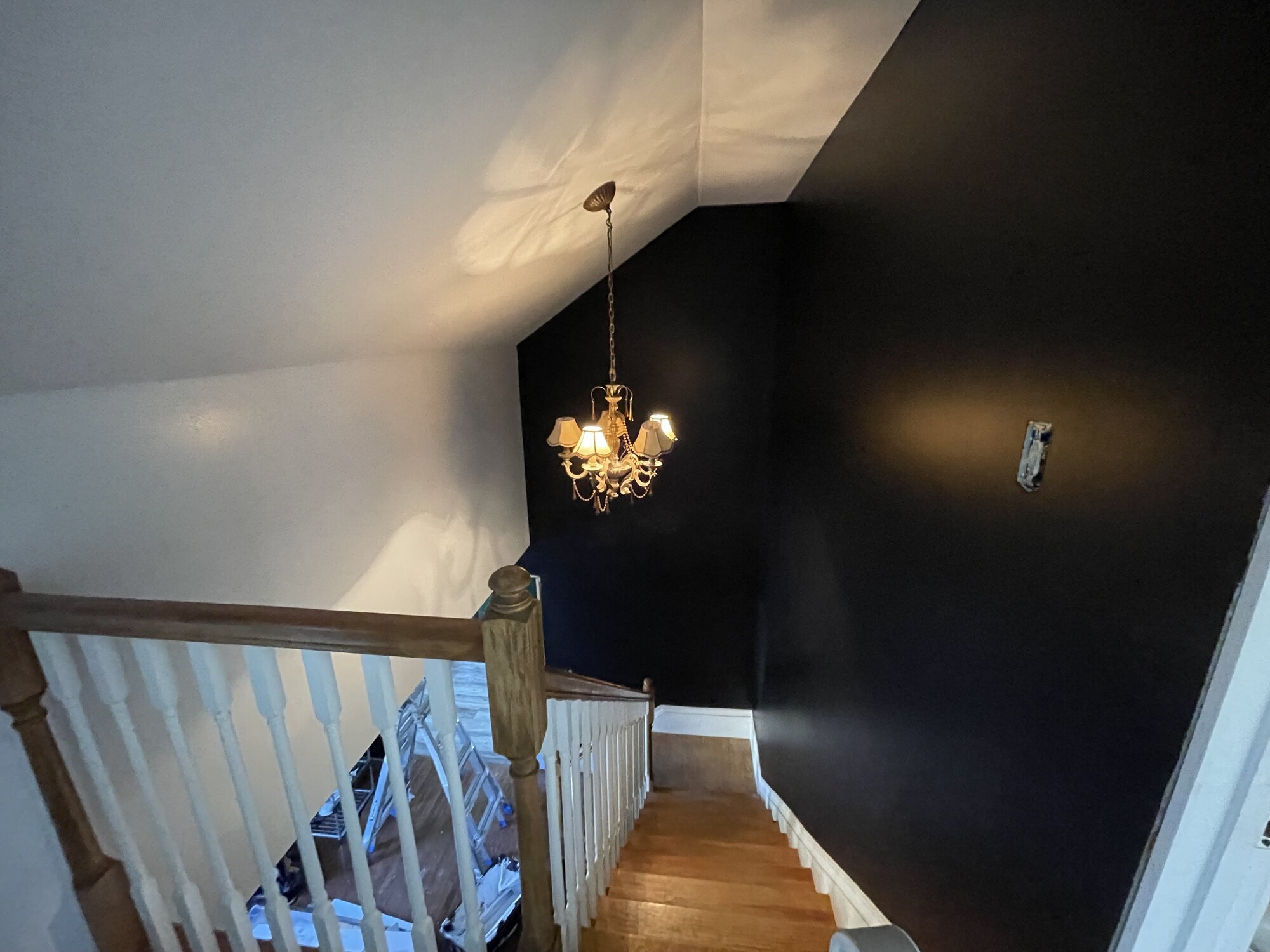 Upstairs landing with a charcoal wall meeting a white angled ceiling above an oak stair rail