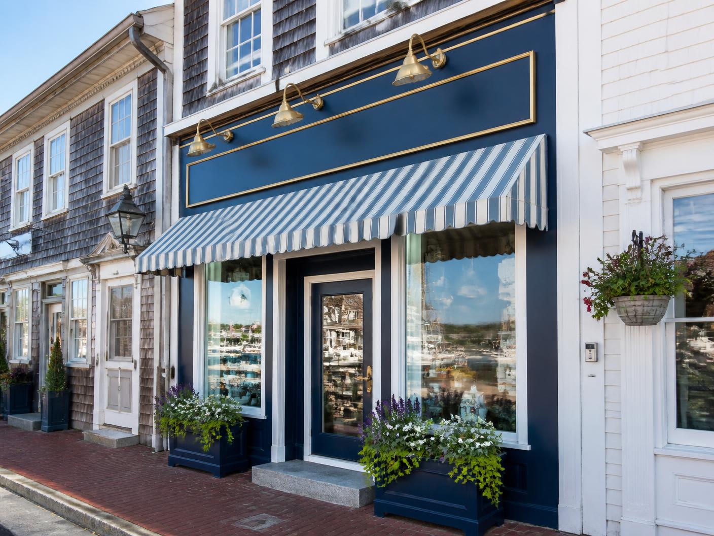 Historic main street shop with a freshly painted deep blue facade, striped awning, and window boxes